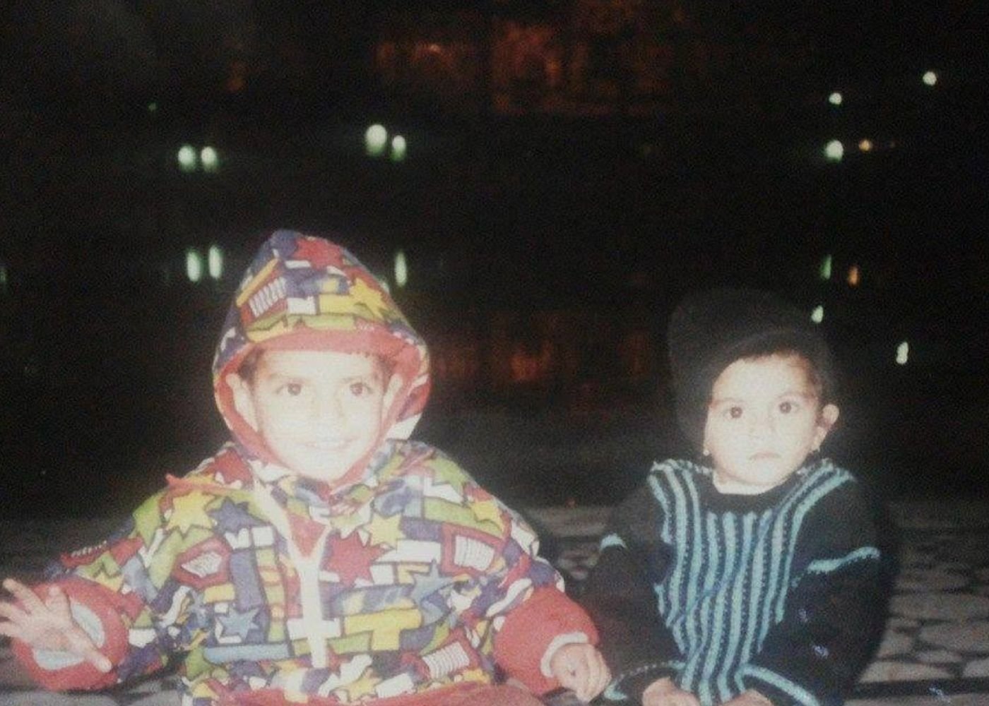 Nikunj as a young boy and baby Divyanshi sitting together outdoors at night