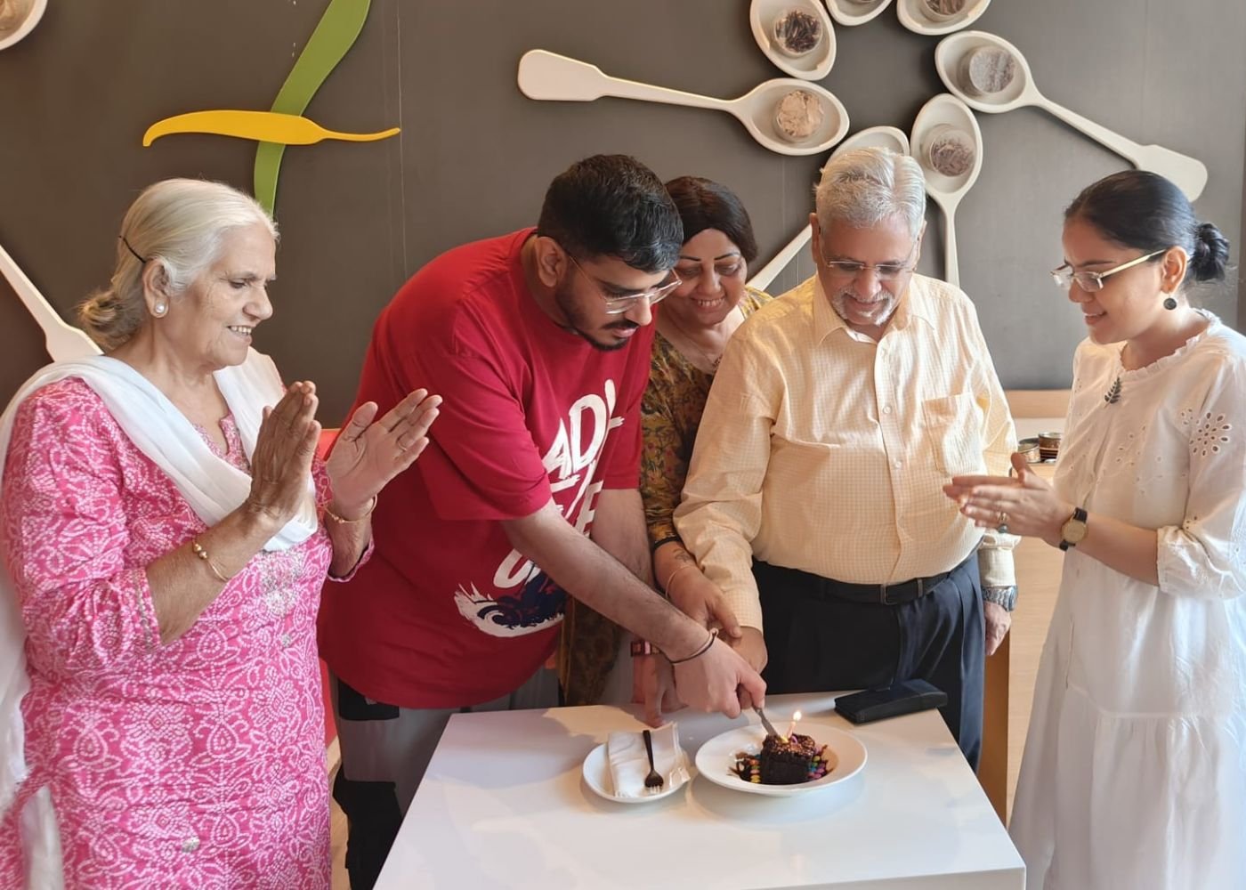The whole family gathered around a table, cutting a birthday cake together